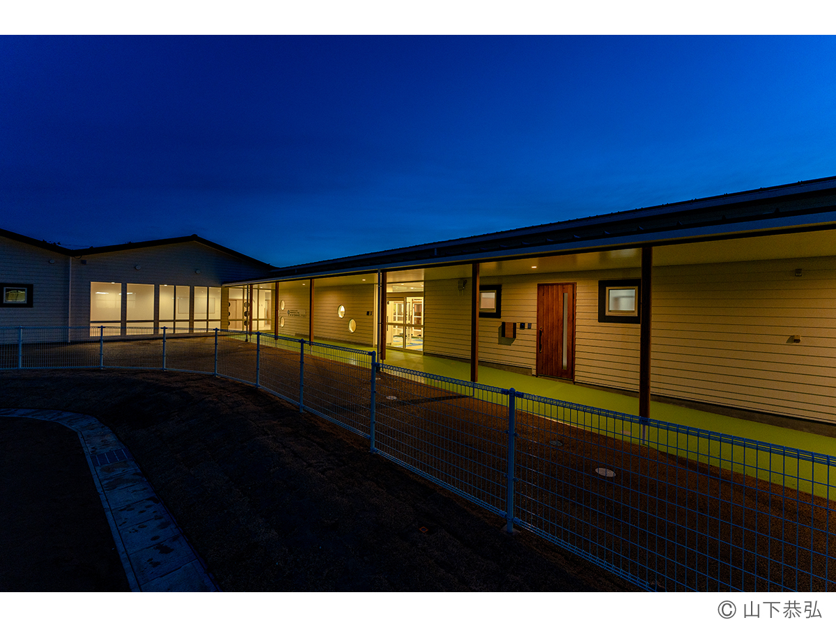 切妻屋根が連続するわくわくゆめの樹こども園外観夕景2